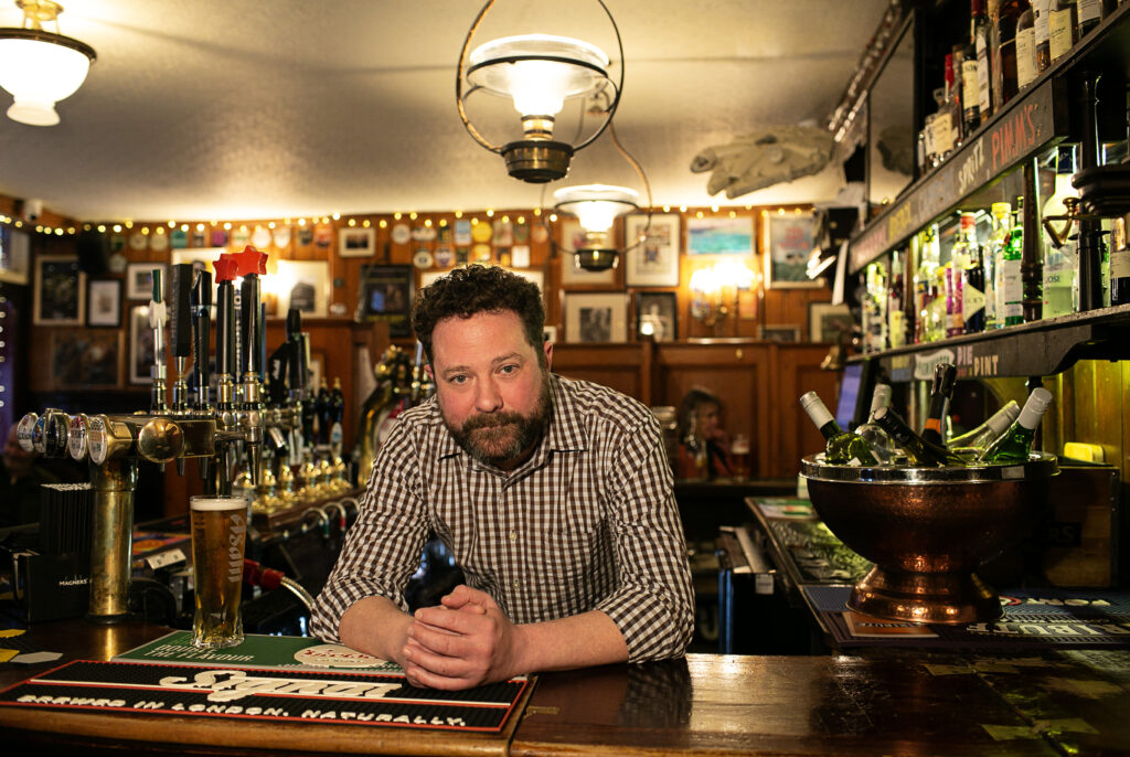 A bartender is staying behind the counter The Barley Mow, the oldest pub in Marylebone