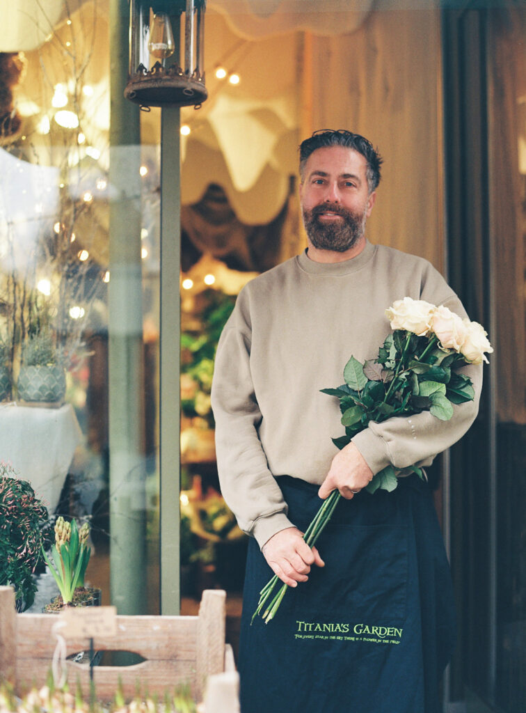 Michael is holding a rose bouquet in front of Titiana's Garden, a flower shop in Marylebone